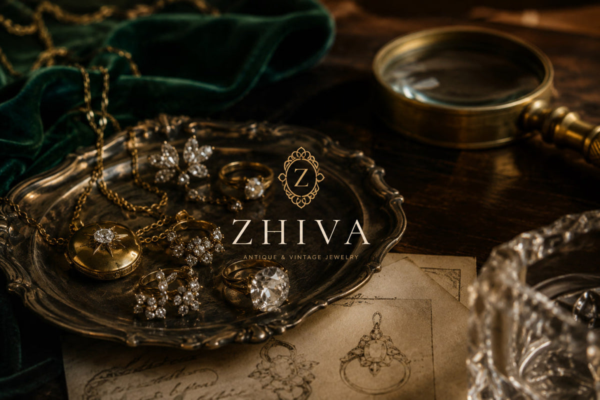 Antique gold jewelry on a silver tray beside hand-drawn antique jewelry designs on aged paper.